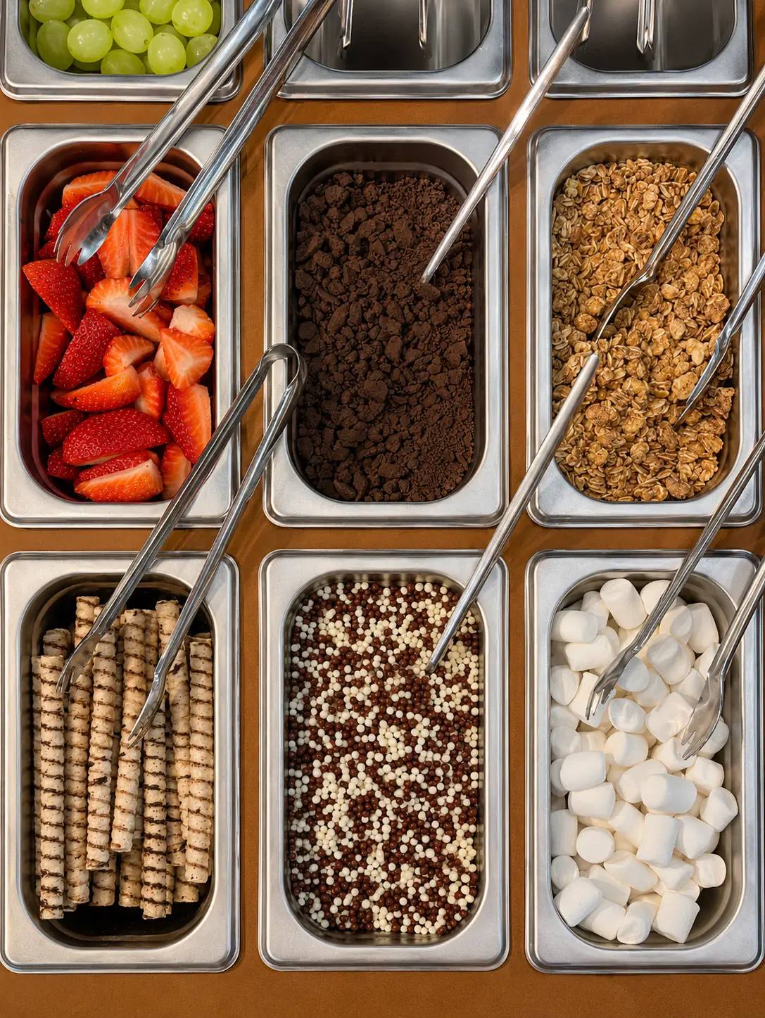 Bandejas com morango, granola, chocolate, marshmallow e outros acompanhamentos da estação gourmet